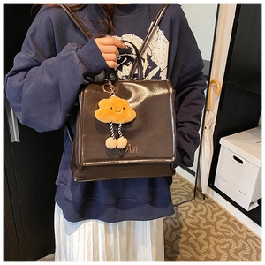 Detail of dark brown glossy leather backpack with nem embroidery and plush cloud charm
