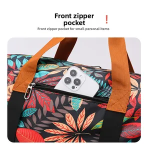 Detail of front zipper pocket on floral travel bag showing storage space for a smartphone