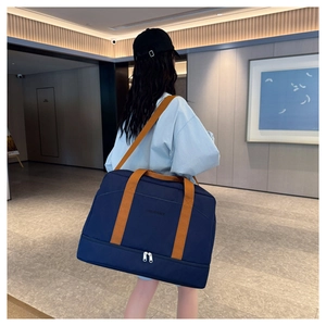 Détail du sac de voyage bleu avec anses oranges et compartiment chaussures séparé