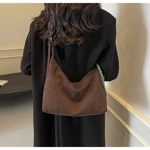 Detail of dark brown suede bucket bag with green woven cord and leather strap texture