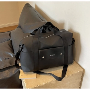 Dettaglio della borsa da viaggio nera impermeabile con manici robusti e tasca borchiata