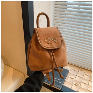 Detail eines braunen Wildleder-Mini-Rucksacks mit goldener Schleife und Kordelzugverschluss