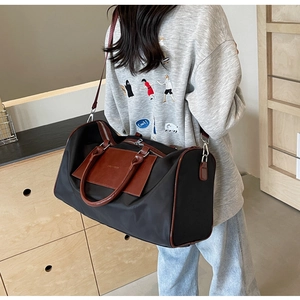 Large capacity black travel bag with leather handles shown in a home interior setting