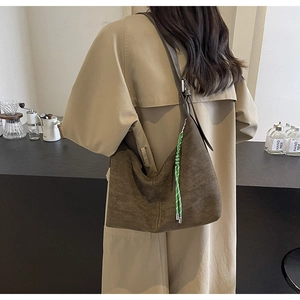 Brown suede hobo shoulder bag with a vibrant green braided cord accent shown on model