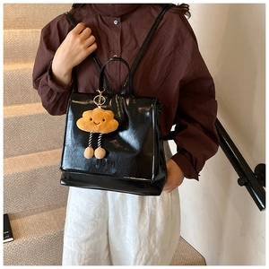 Close-up of black glossy leather backpack with 19m logo and cute cloud plush charm