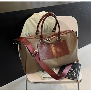 Detailed close-up of large travel bag with burgundy leather straps and khaki fabric