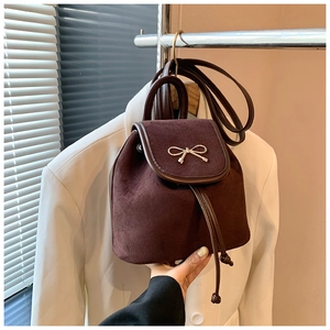 Detail eines dunkelbraunen Mini-Rucksacks aus Wildleder mit goldener Schleife und Kordelzug