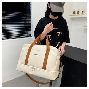 Vue détaillée du sac de voyage crème montrant les sangles brunes et le compartiment à chaussures