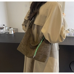 Detail view of brown suede bucket bag featuring a contrasting green woven rope accent