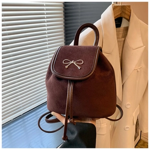 Detail eines braunen Wildleder-Mini-Rucksacks mit Metallschleife und Kordelzugverschluss