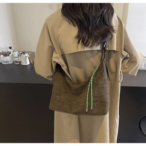 Gros plan du sac hobo vintage en daim marron avec cordon tressé vert et bandoulière
