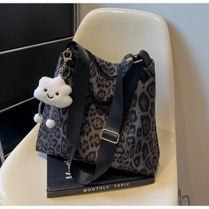 Detail der Leopard-Tasche mit Plüsch-Wolkenanhänger und verstellbarem Nylon-Schultergurt