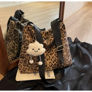 Detail der Leopard-Tasche mit weißem Plüsch-Wolkenanhänger und breitem Gurt
