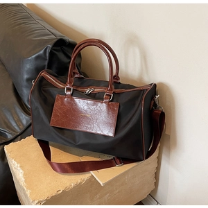 Detail of travel bag with black fabric, brown leather handles and silver metal hardware