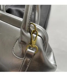Dettaglio borsa in pelle argentata con chiusura e finiture in metallo dorato lucido