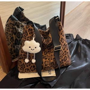 Detail der Leopard-Tasche mit weißem Plüsch-Anhänger und breitem schwarzen Schultergurt