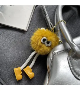 Dettaglio del ciondolo mostro di peluche giallo con catena su una borsa argento