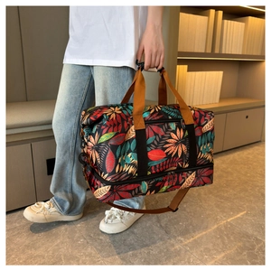 Détail du sac de voyage imprimé feuilles tropicales avec anses brunes et double zip