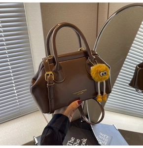 Dettaglio della borsa in pelle lucida marrone scuro con ciondolo a mostro in peluche