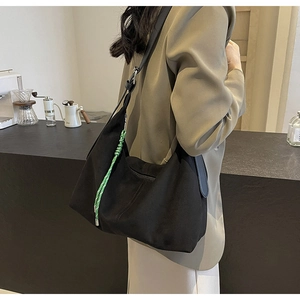 Detail of black nylon bucket bag with green woven rope charm in a lifestyle setting