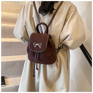 Brauner Wildleder-Mini-Rucksack mit Schleife, getragen am Rücken des Models
