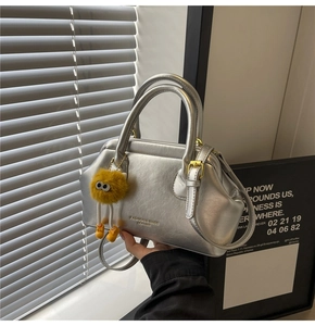 Dettaglio della borsa metallizzata argento con logo a rilievo e ciondolo a mostriciattolo