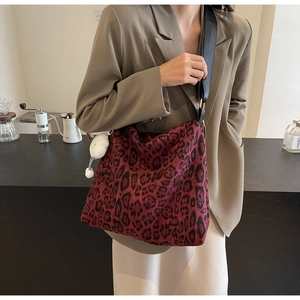 Detail der dunkelroten Shopper Tasche mit Leopardenmuster und weißem Plüsch-Anhänger
