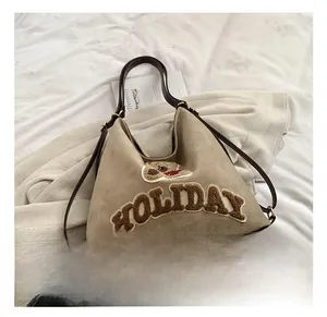 Detail of khaki tote bag with plush Holiday letters and bear patch on matte fabric