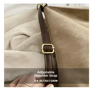 Close-up of adjustable strap buckle on beige suede tote bag with brown leather detail