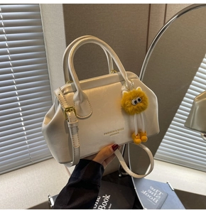 Dettaglio borsa in pelle crema con fibbia dorata e simpatico ciondolo in peluche giallo