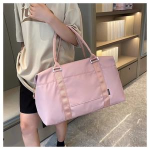 Pink waterproof travel bag shown being carried by a model in a lifestyle setting