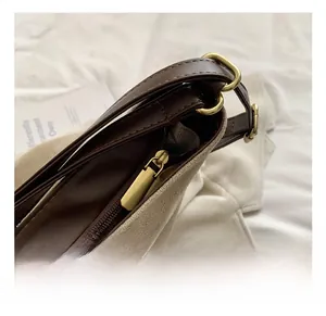 Detail showing high-quality gold zipper and hardware on a brown and beige patchwork tote bag