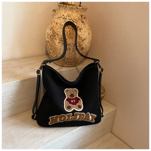 Detail of black canvas Hobo bag with plush bear patch and 3D Holiday lettering
