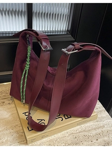 Vintage burgundy suede hobo bag with adjustable strap on a minimalist aesthetic background