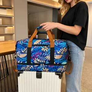 Detail of travel bag with tropical leaf print mounted on a white suitcase handle