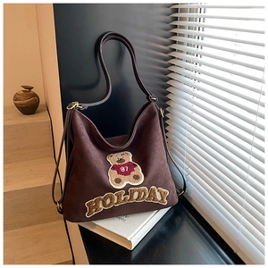 Detail of dark brown faux suede tote featuring teddy bear patch and holiday embroidery