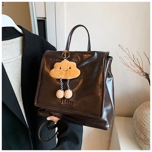 Detail view of coffee oil wax leather backpack with Hbm embossing and plush cloud charm