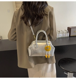 Borsa a mano argento metallizzato con ciondolo a mostro giallo indossata da modella