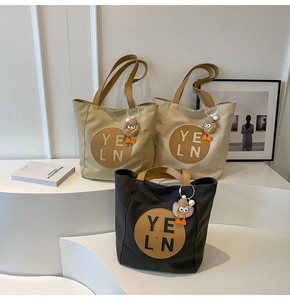 Three canvas tote bags in khaki, white, and black with plush chick charms