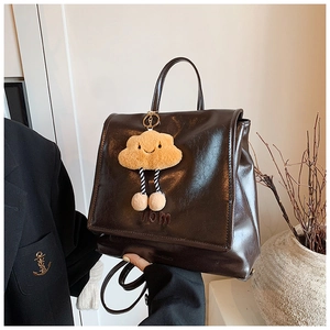 Detail of dark brown glossy leather backpack with Vbm embroidery and cloud charm
