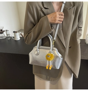 Borsa a mano argento con ciondolo a mostro indossata da modella in blazer marrone