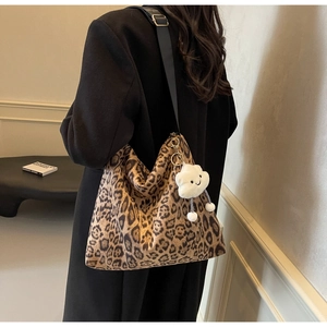 Detail der Leopard-Tasche mit weißem Plüsch-Cloud-Anhänger und breitem Schultergurt
