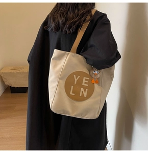 Fashionable beige canvas tote bag with brown leather patch and cute plush duck charm