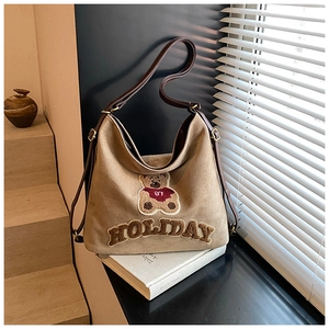 Close-up of a vintage canvas tote bag featuring an embroidered plush bear and 87 lettering