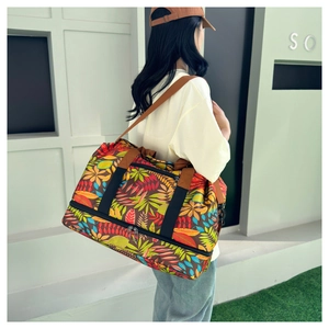 Détail du sac de voyage à imprimé tropical avec compartiment chaussures et poignées brunes