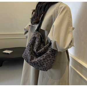 Detail of a large leopard print tote bag with black leather strap on a model shoulder