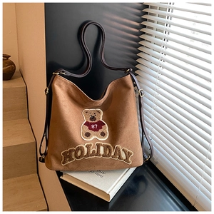 Detail view of brown suede tote bag featuring a teddy bear patch and holiday embroidery