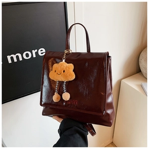Detail of burgundy glossy leather backpack with mom embroidery and plush charm