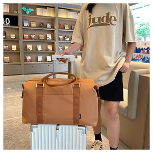 Detail of tan travel bag showing the trolley sleeve functionality on a white suitcase