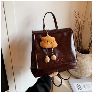 Detail of vintage brown leather backpack with mbm embroidery and yellow cloud charm